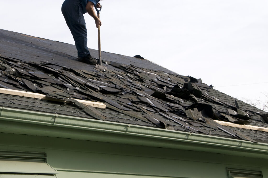 man on damaged roof with broken shingles
