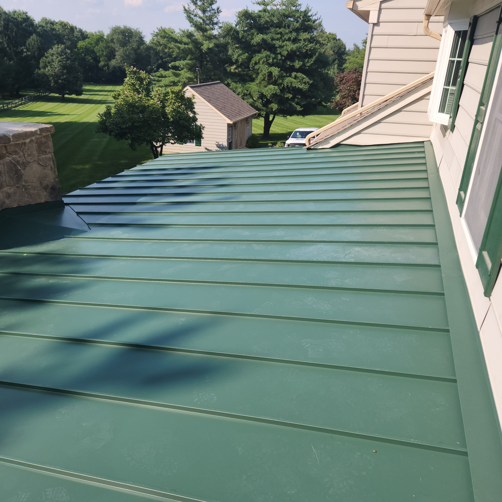 Top-view of a dark green roof on a home with tan siding.